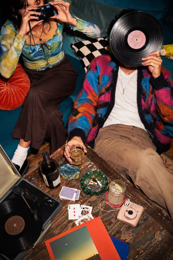 Two friends with a record player, film camera, and vinyl in a living room